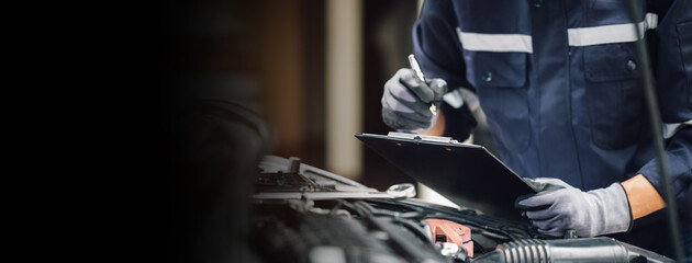 Car service, repair, maintenance concept,auto mechanic man or Smith writing to the clipboard at workshop, technician doing the checklist for repair machine a car in the garage,banner.