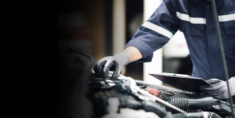 Mechanic works on the engine of the car in the garage. Repair service. Concept of car inspection service and car repair service.