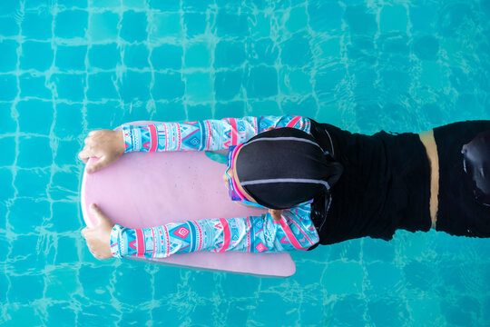 Top view Asian child little girl swims with board in the pool. Swimming lesson idea concept