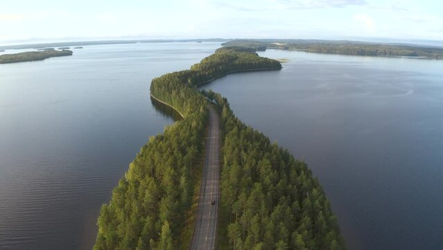Car driving a unique road going through islands in the middle of a lake at Pulkkilanharju in Finland
