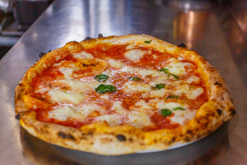 Pizza margherita napoletana fumante e appena sfornata con sugo di pomodoro, mozzarella di bufala e basilico fresco 