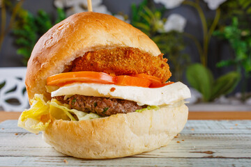Panino ripieno di hamburger di carne macinata, medaglione di patate, pomodori, fior di latte e insalata 