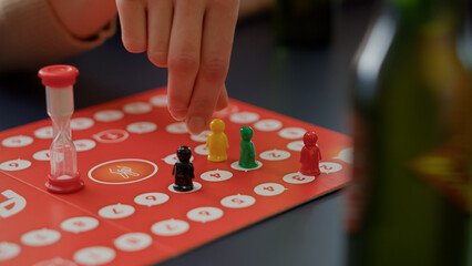 Young people playing charades board games with figurines, rolling dices for cards game. Men and...