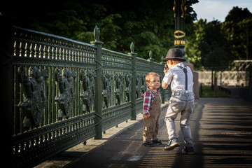 Obraz premium A boy is taking a photo of his little brother on bridge in city