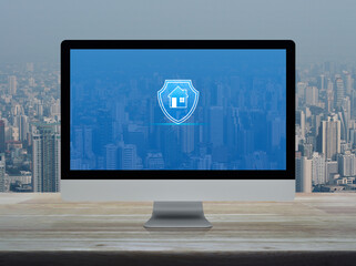 Home with shield flat icon on desktop modern computer monitor screen on wooden table over office building tower and skyscraper in city, Business home insurance and security online concept