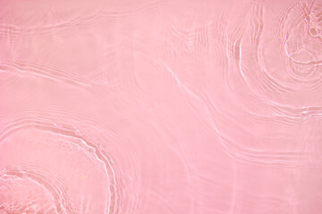 Transparent pink colored clear water surface texture with ripples, splashes and bubbles. Abstract...