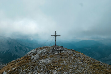Fototapeta na wymiar Scenic view from the summit cross of mount Zinken in the Hochschwab Region, Upper Styria, Austria. Valley is covered with clouds. Weather change on rainy spring day in the Alps, Europe. Alpine terrain
