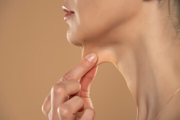 A close-up and side profile view of a caucasian lady pinching the loose skin at the front of her throat. Commonly called a turkey neck and corrected with a platysmaplasty - obrazy, fototapety, plakaty
