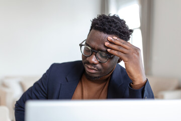 Stressed tired African American man touching temples, suffering from headache after long hours...