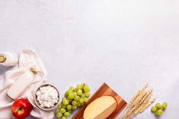 Shavuot flat lay with dairy products, first fruits and wheat on light gray background