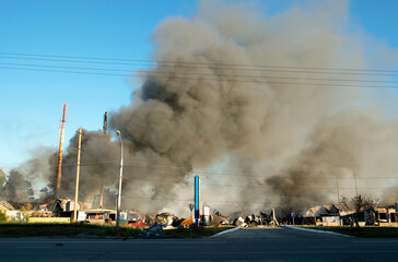 A huge cloud of smoke from an explosion and fire on the outskirts of the city against the blue sky