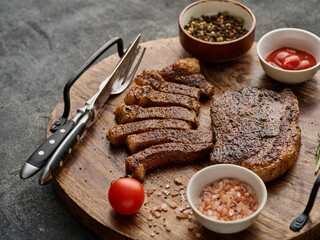 Grilled top sirloin or cup rump beef meat steak on wooden board. Dark background. Picanha steak