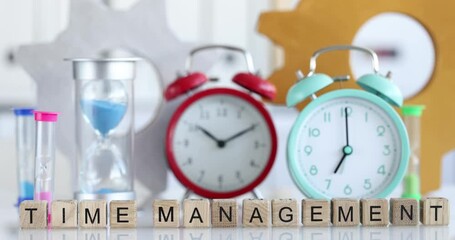 Text time management alarm clock and hourglass on table