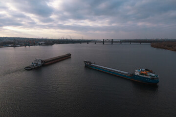 The cargo ship arrives at the river port. View from above. Panoramic view of the city. Barge floating on the Dnieper River, Ukraine. Bird's-eye view.