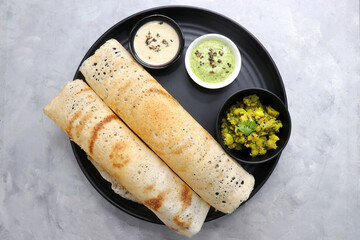 Crispy Masala dosa is a popular South Indian food item served with tomato chutney, coconut chutney, spicy potato masala, or aloo ki sabzi and sambar. Copy space. Crunchy Rice crepes.