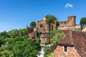 Сommoner settlement located on hill slopes and fortress castle Chateau de Castelnau-Bretenoux in...
