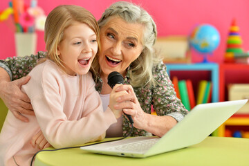 portrait of happy grandmother and daughter singing karaoke