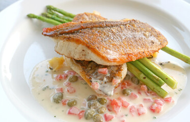 Closeup of delectable pan seared sea bass with tomato caper mustard cream sauce