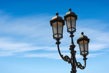 Fototapeta na wymiar Close-up of old street lamp posts against a clear blue sky with clouds and copy space. Loggia town square (Piazza della Loggia), Brescia downtown, Lombardy, Italy, Southern Europe.