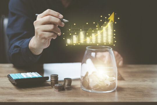 Business Finance and Money Save money concept, man calculating accounting numbers to estimate income expenditure and income His right hand holds a pen and draws a realistic gold graph growth.