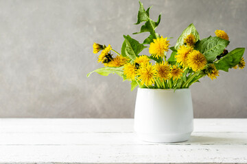 Mock up creation. White wooden table with grey concrete background, dandelions in vase and copy space on the left