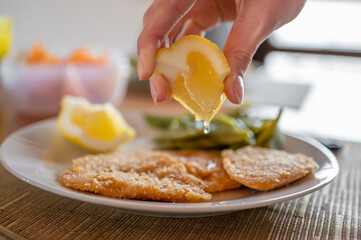 Hand queezing lemon on vegan chickpea cutlet.