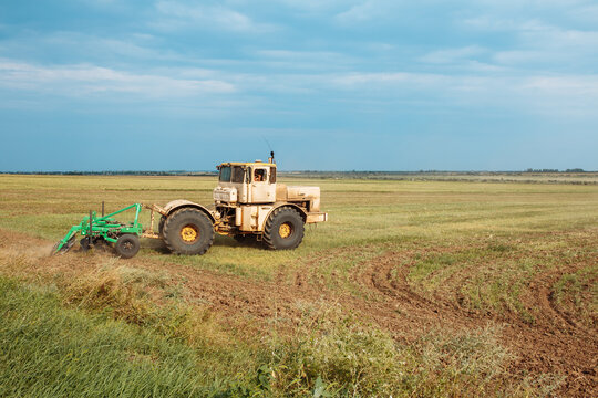 Tractor cultivating field. Plowing fields. Preparing land for sowing. Rich harvest concept.