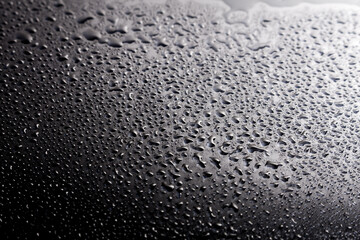 Dark shiny surface with droplets. Close up image of wet shiny background.