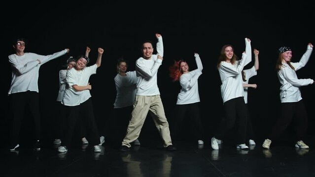 A team of dancers in white t-shirts are dancing a cheerful dance of several synchronized movements, they can be a support group