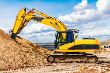 Two powerful excavators work at the same time on a construction site, sunny blue sky in the background. Construction equipment for earthworks.