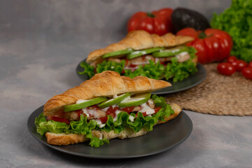 Croissant sandwich with turkey ham, tomatoes, cheese and lettuce salad. Continental style breakfast