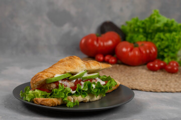 Croissant sandwich with turkey ham, tomatoes, cheese and lettuce salad. Continental style breakfast