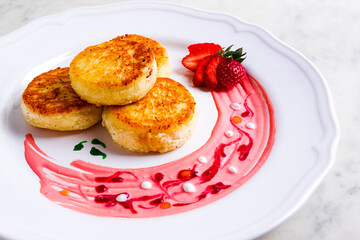 Cottage cheese pancakes, on a white plate decorated with sauce, fresh strawberry berry, close-up, no people,