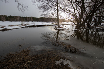 Spring landscape with a river. Snow melts in March. Evening in early spring.