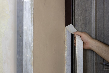 A man tears off masking tape after plastering work.