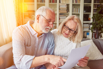 Couple of seniors reading contract or insurance at home - obrazy, fototapety, plakaty