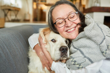 Senior woman hugs her large retriever dog at home