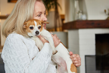 Old woman cuddles with her lap dog at home