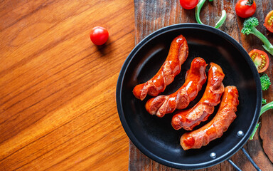 Fried sausages in a pan with tomatoes and broccoli