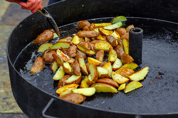 Street food. Potatoes fried in a large pan. Delicious fast food.