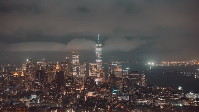Aerial panorama shot of mystic fog surrounding one world trade center and skyscraper of New York City at night - time lapse 