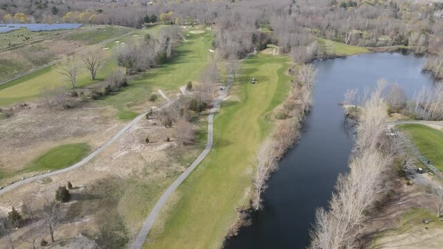 Gentle push forward over Widow's Walk Golf Course in Scituate, MA USA. Water hazard, golfers, fairways revealed.