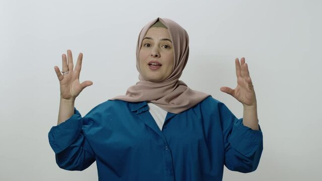 The hijab woman is very angry at what happened.Indoor studio shot isolated on white background. The woman is making fun of the interlocutor by making gestures or something.