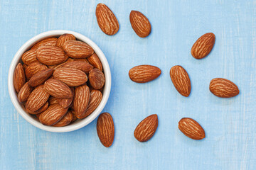 Almonds in white bowl on blue wooden table