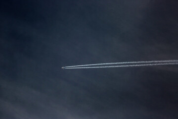 plane with condensation trail on dark blue sky