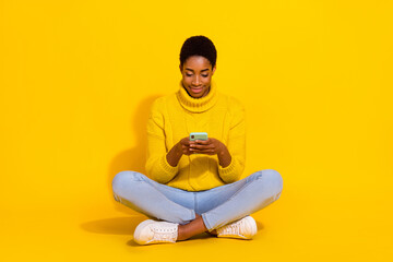 Portrait of attractive focused cheery girl sitting on floor using device post app 5g isolated on...