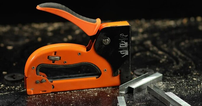 Orange construction stapler and a stack of staples for the stapler in workshop, Profession, carpentry and woodwork concept,