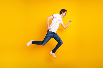 Full body profile side photo of young man jump run fast discount wear denim isolated over yellow color background