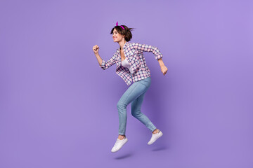 Fototapeta na wymiar Photo of charming hurrying lady dressed checkered shirt jumping high running fast isolated purple color background