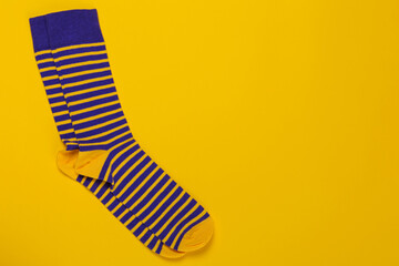 a pair of blue hipster socks with yellow stripes, on a yellow background